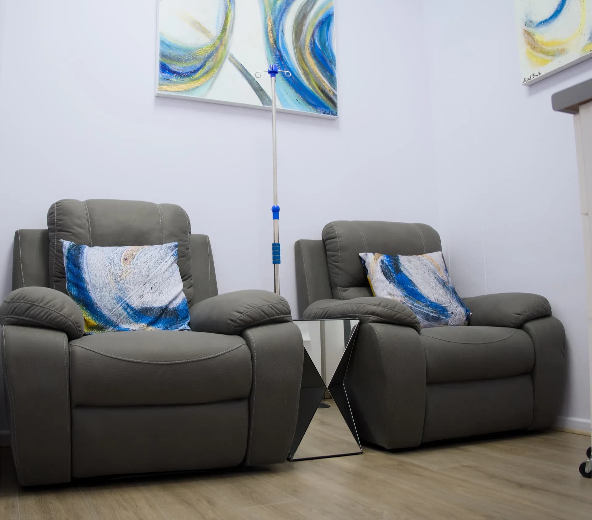 IV therapy room with grey recliners and original abstract art.